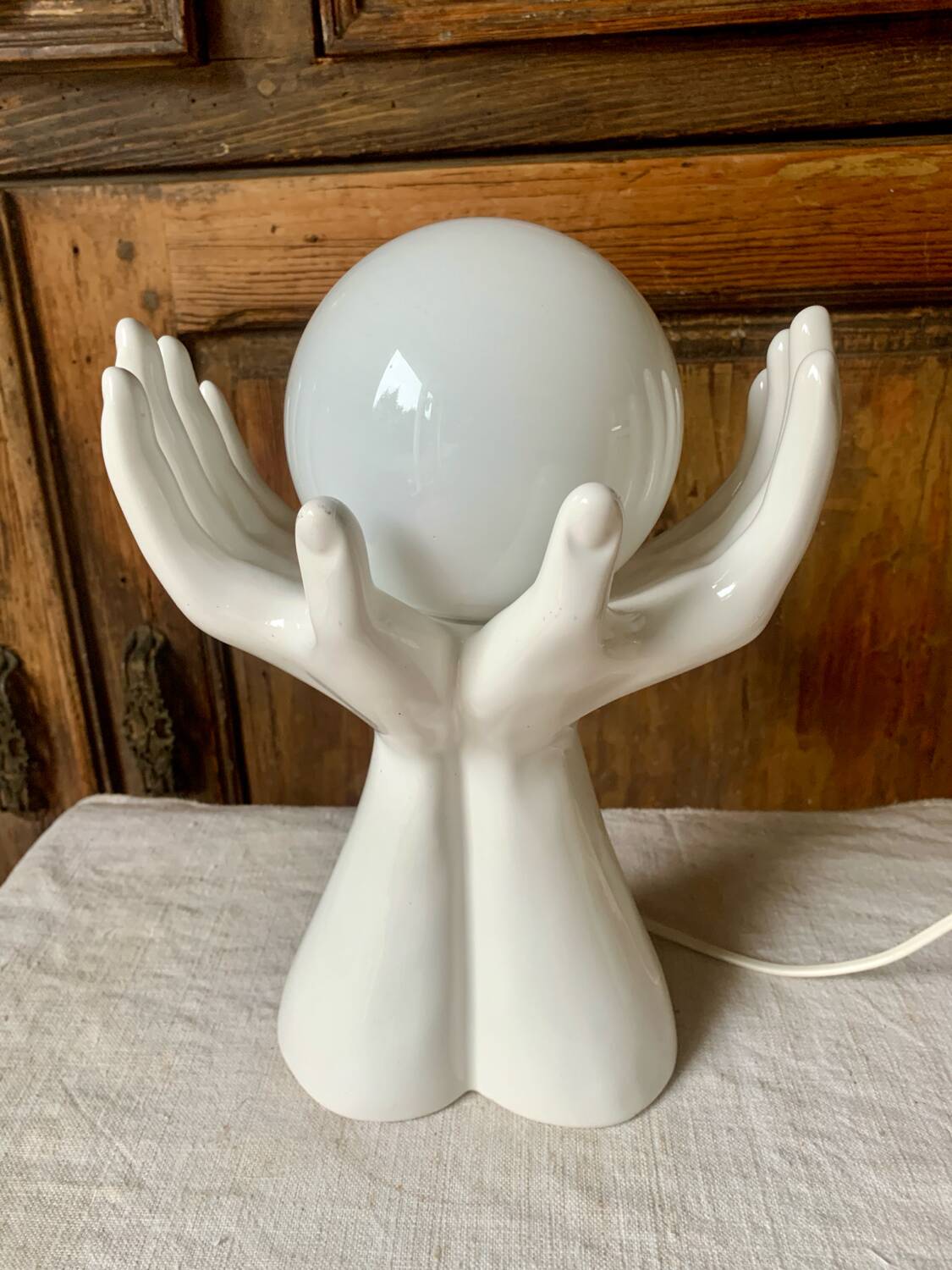 Ceramic table lamp depicting two hands holding a globe, 1980