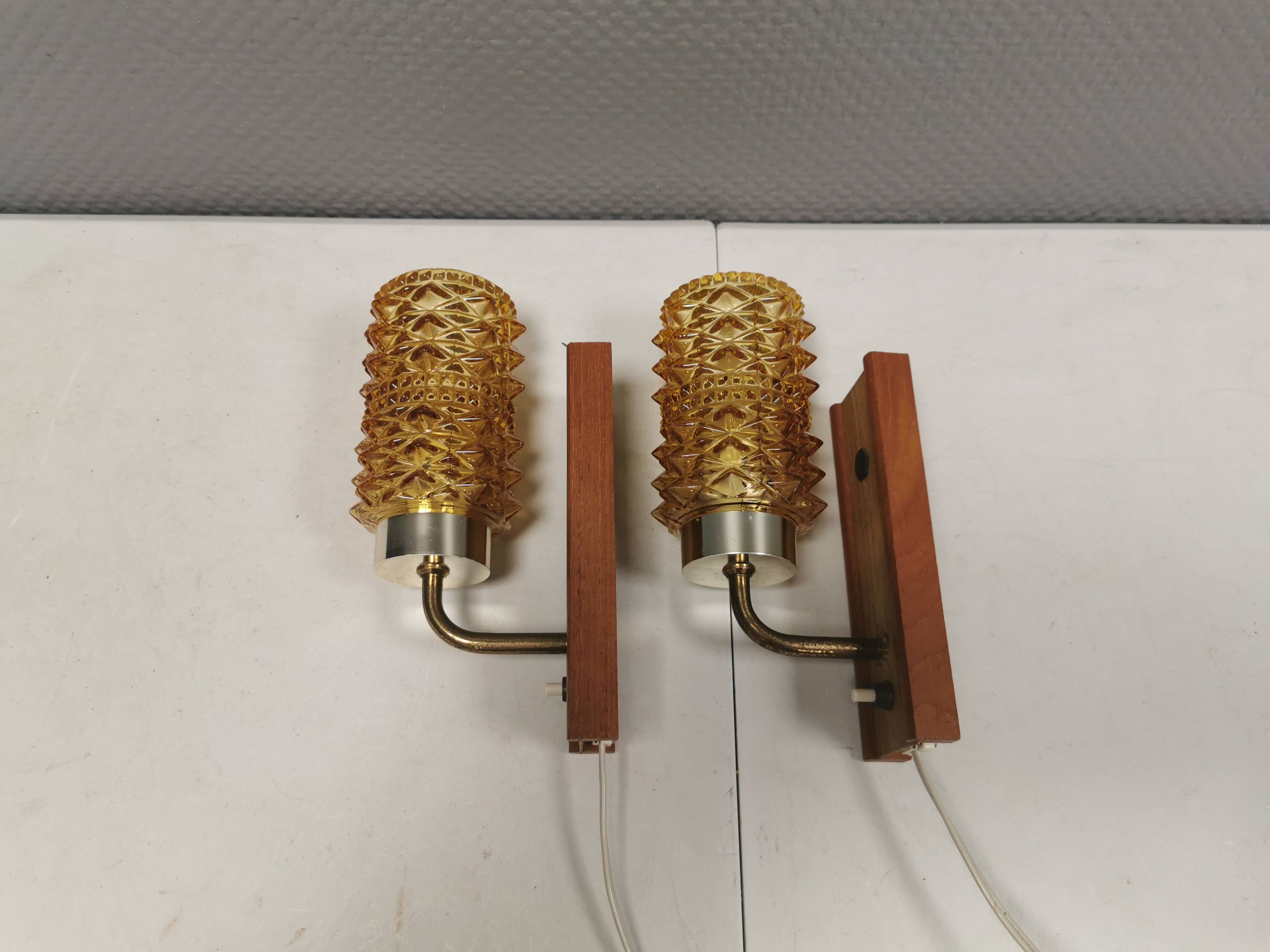 A set of wall lamps in teak wood, with amber colored glass