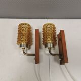A set of wall lamps in teak wood, with amber colored glass