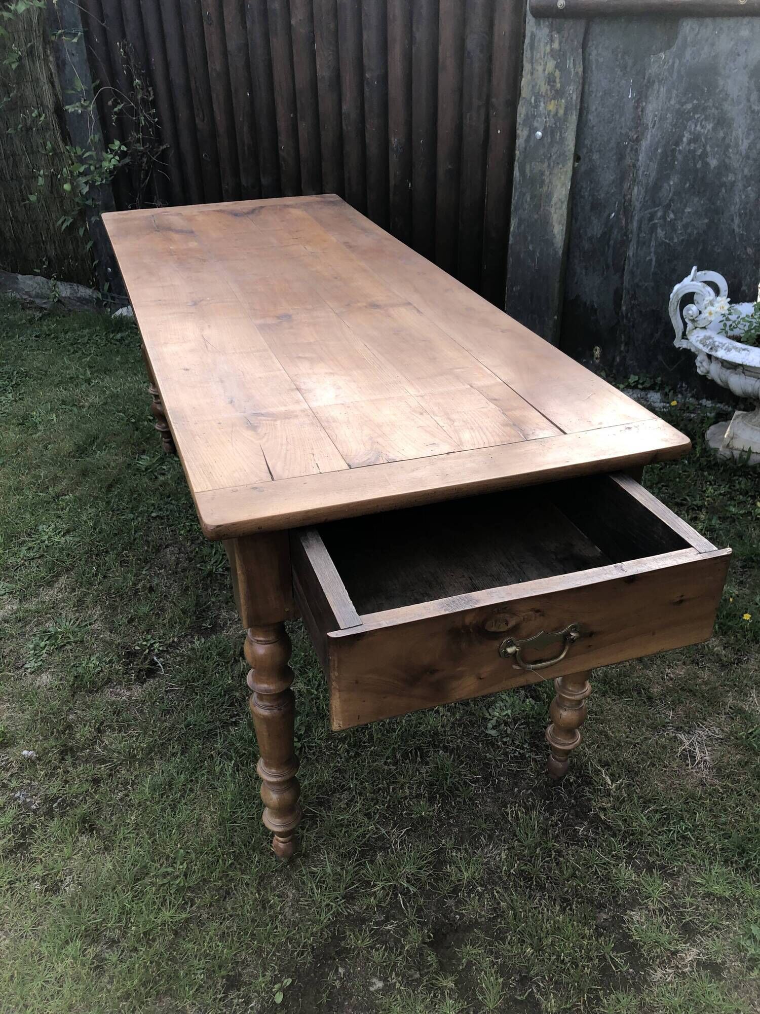 Antique farmhouse table in solid cherry wood with 2 drawers and 1 pull-out at the end with turned legs.
