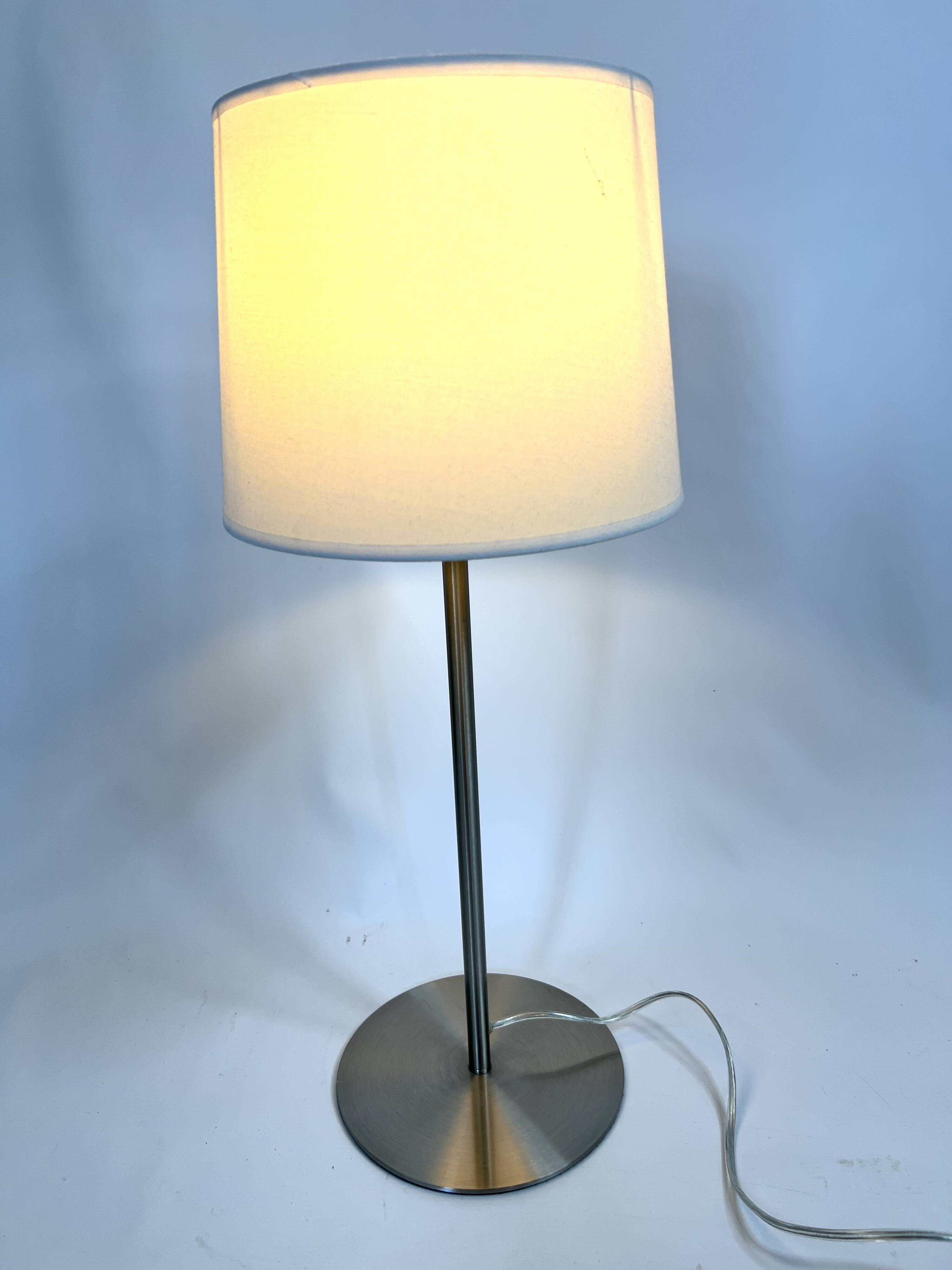 Large brushed metal table lamp with an ecru shade.