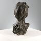 Ancient sculpture of a young woman's face in bronze, 19th-20th century.