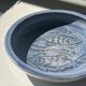 Glazed blue ceramic bowl with stylised fish decoration.