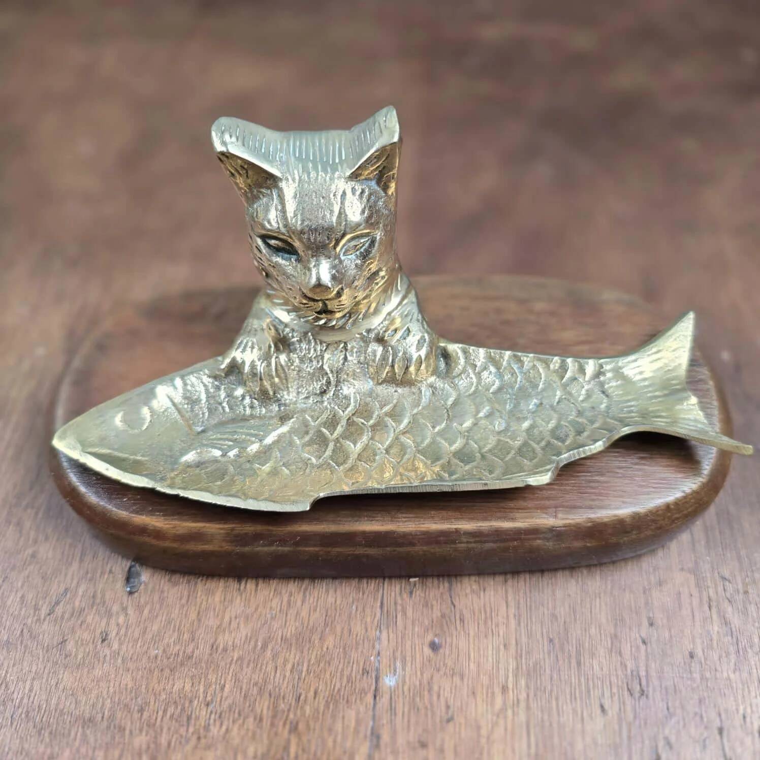 Vintage cat fish catchall in brass on a solid wood base.