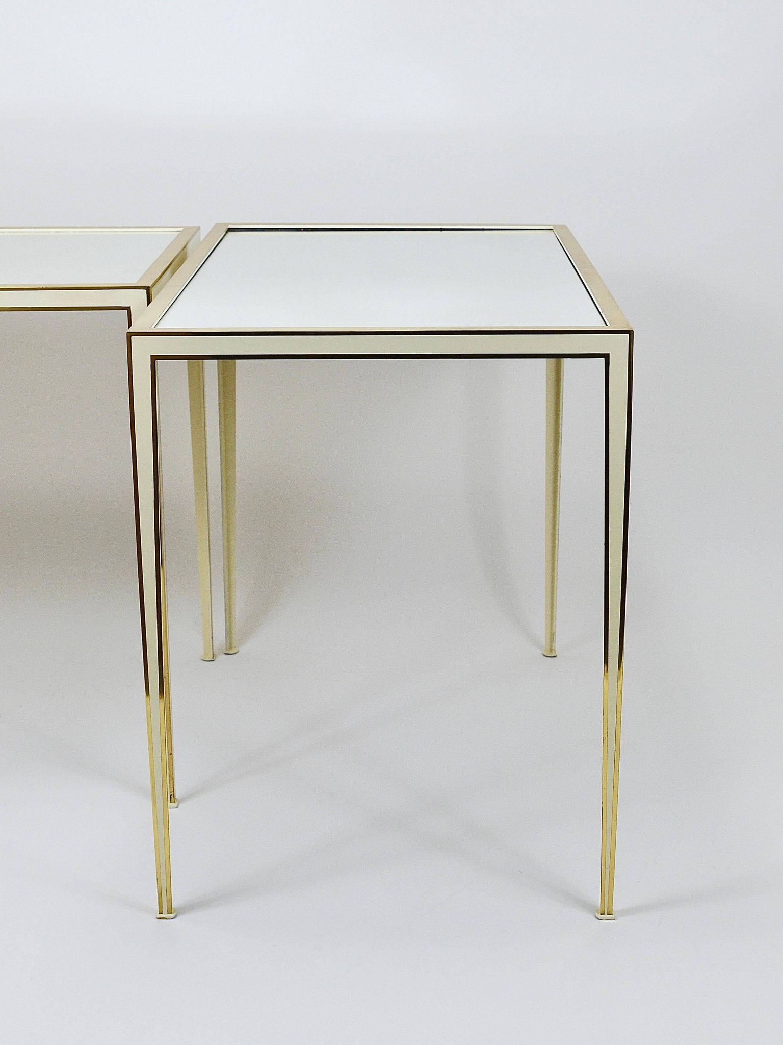 A pair of brass and white mirror tables from Vereinigte Werkstätten, Germany, 1970s.