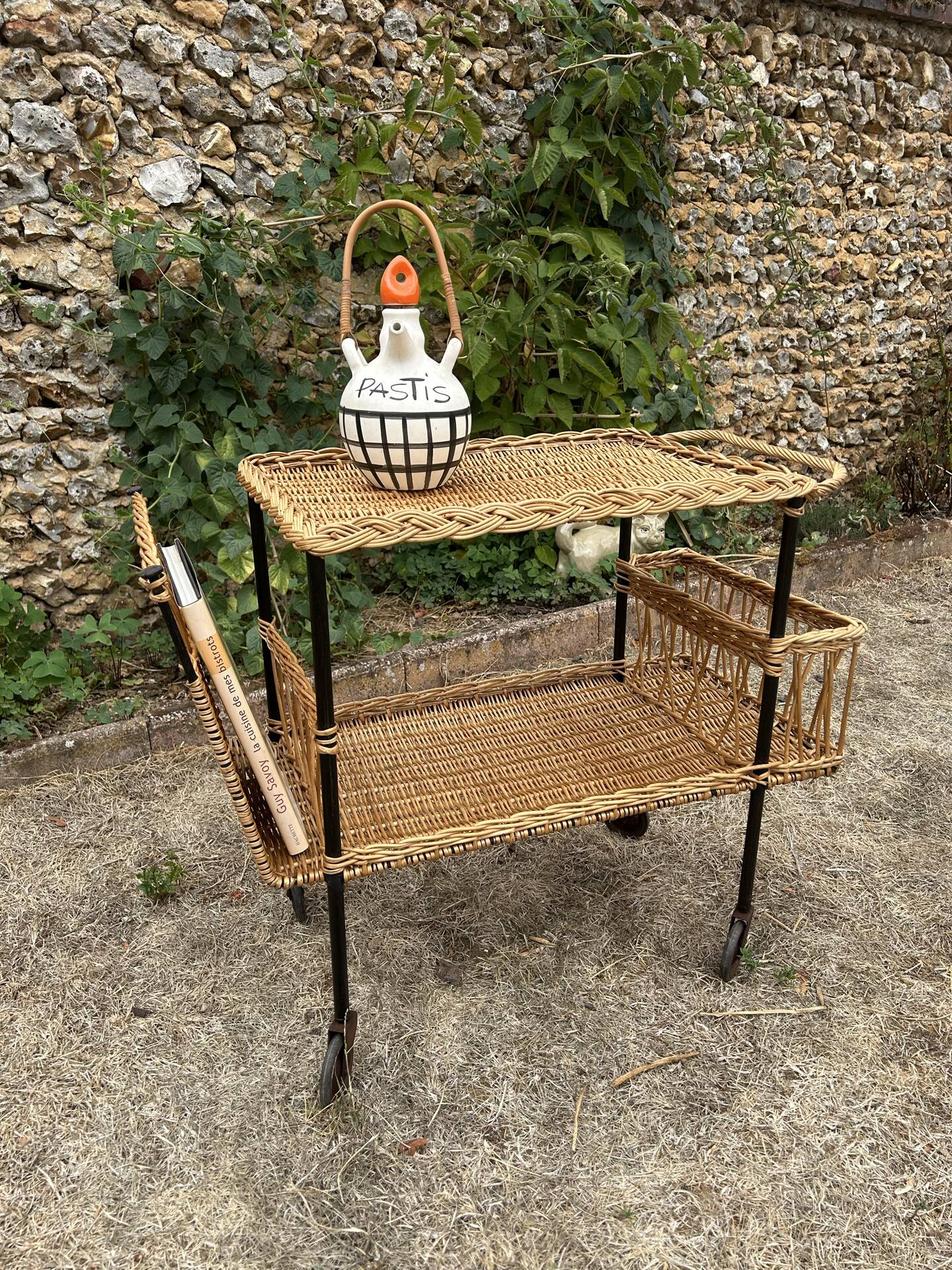 Vintage 1950s rolling dessert trolley in wicker and black tubing.