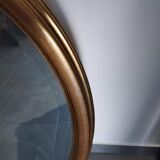 Large and elegant oval gilded mirror with its beveled glass