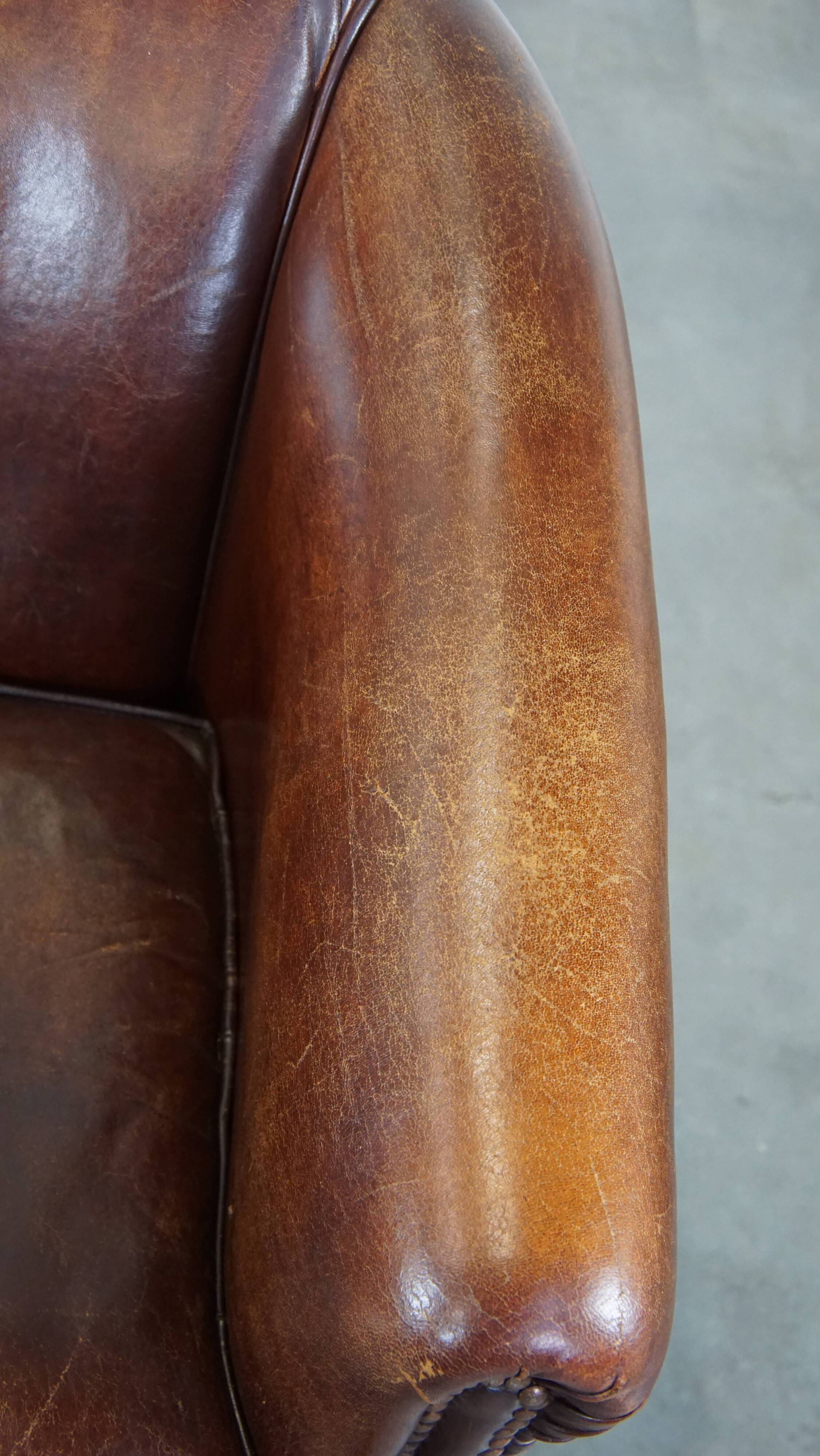 Sheepskin club armchair, correct finishing with decorative nails