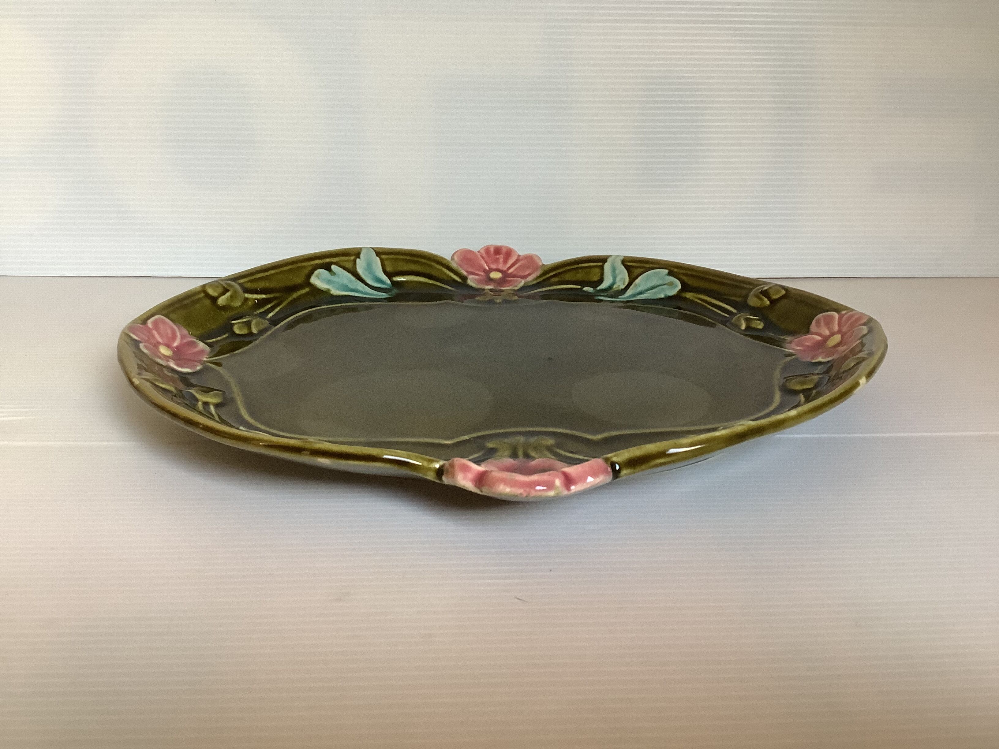 Old khaki green earthenware dish and pink flowers