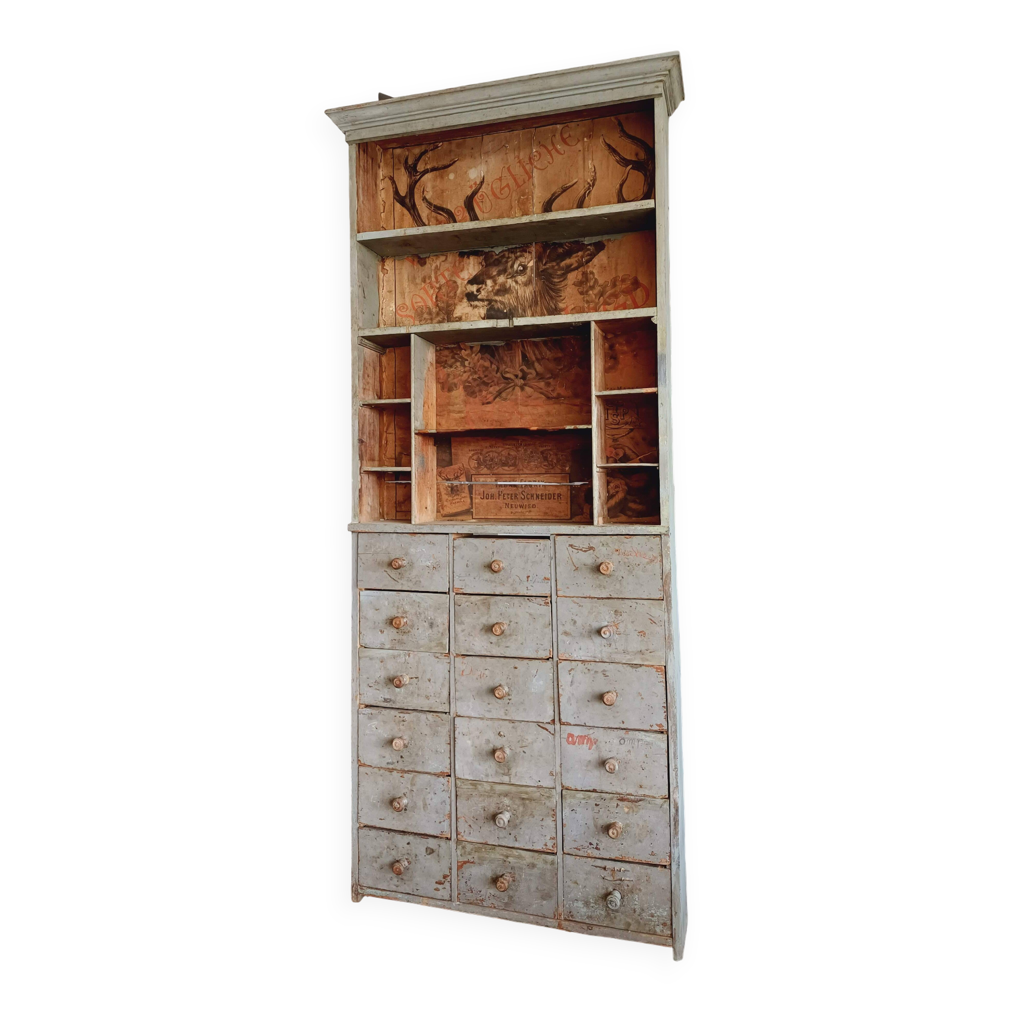 Craft cabinet with drawers with a very old tobacco advertisement in the background