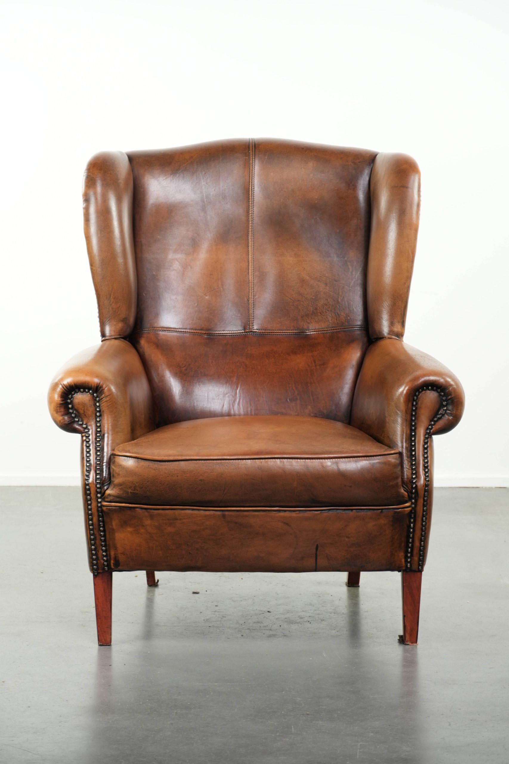 Wingback armchair made of sheepskin leather finished with decorative nails