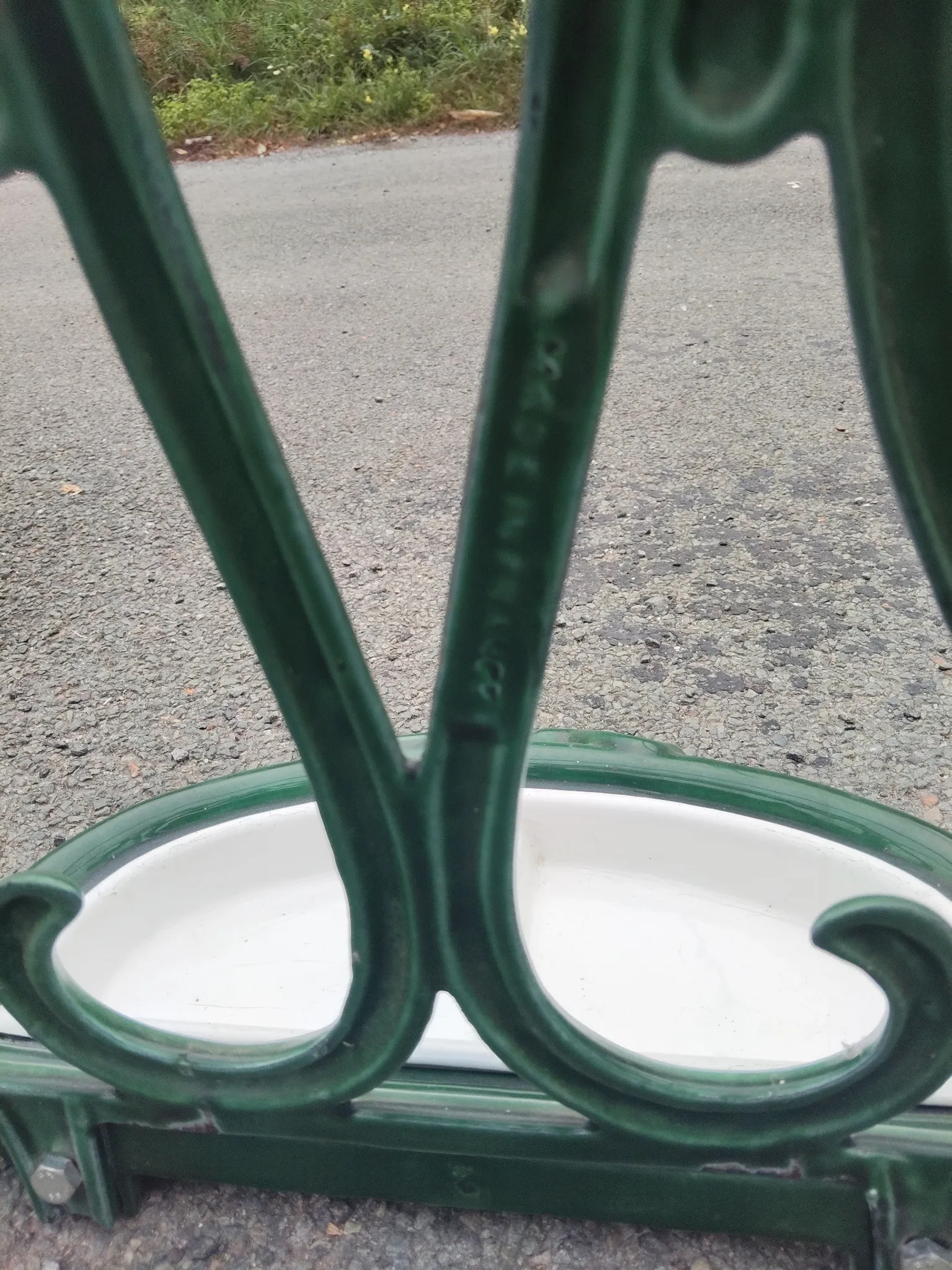 Bottle green enamelled cast iron umbrella stand with a swirl design.