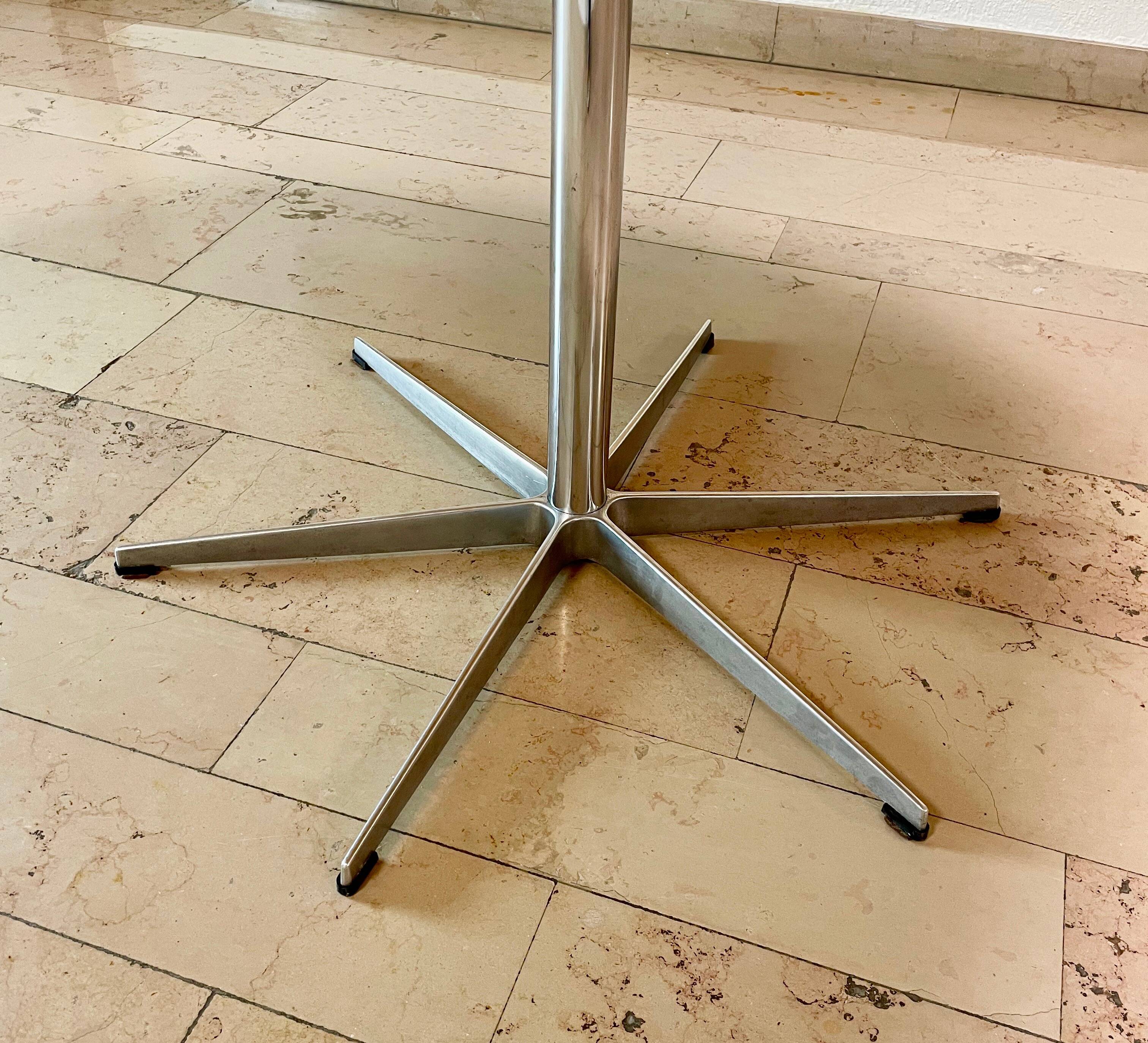 Dining table with a star-shaped six-legged base by Arne Jacobsen for Fritz Hansen.