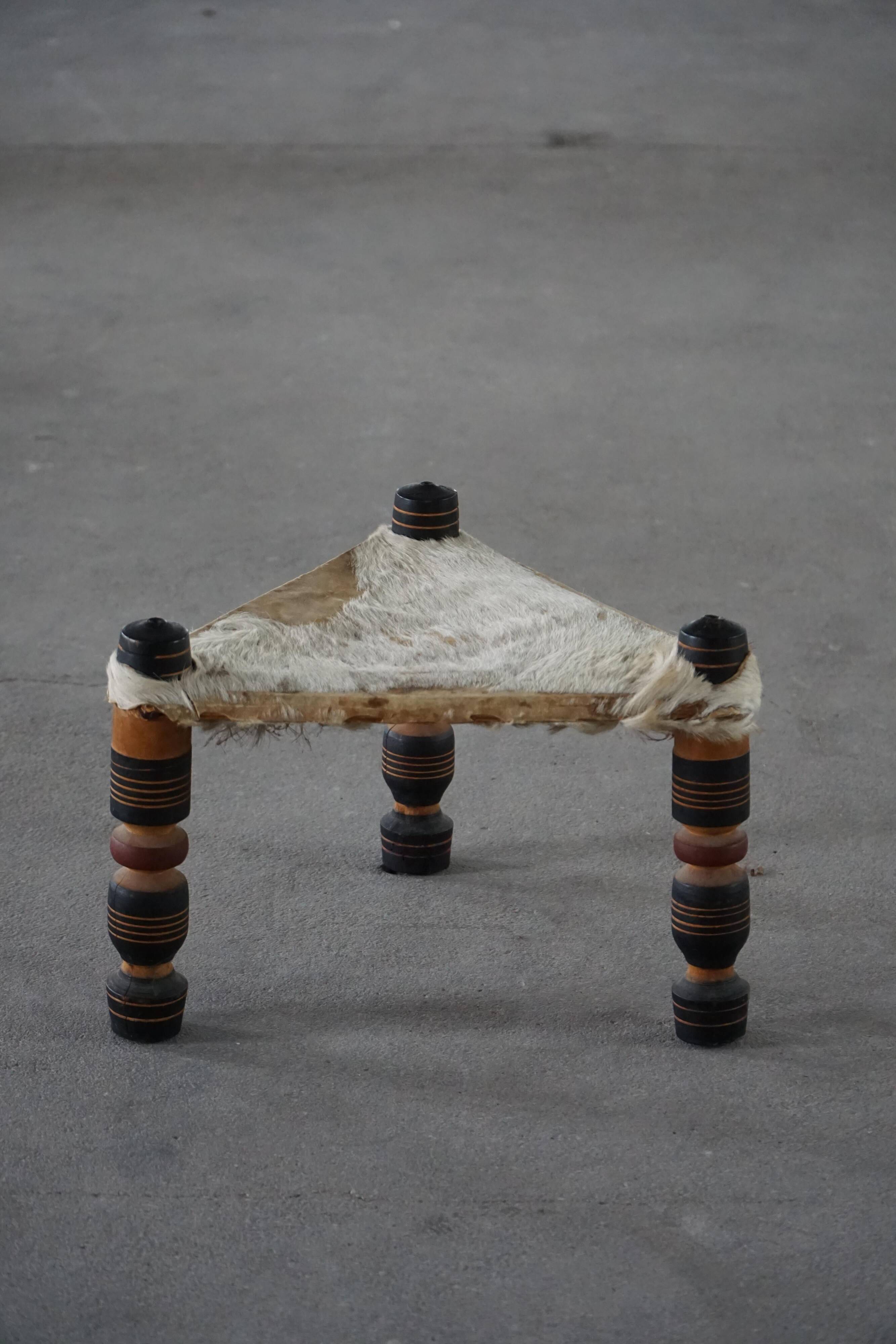 Vintage African artisanal stool, triangular shape with 3 legs, cowhide, 20th century.