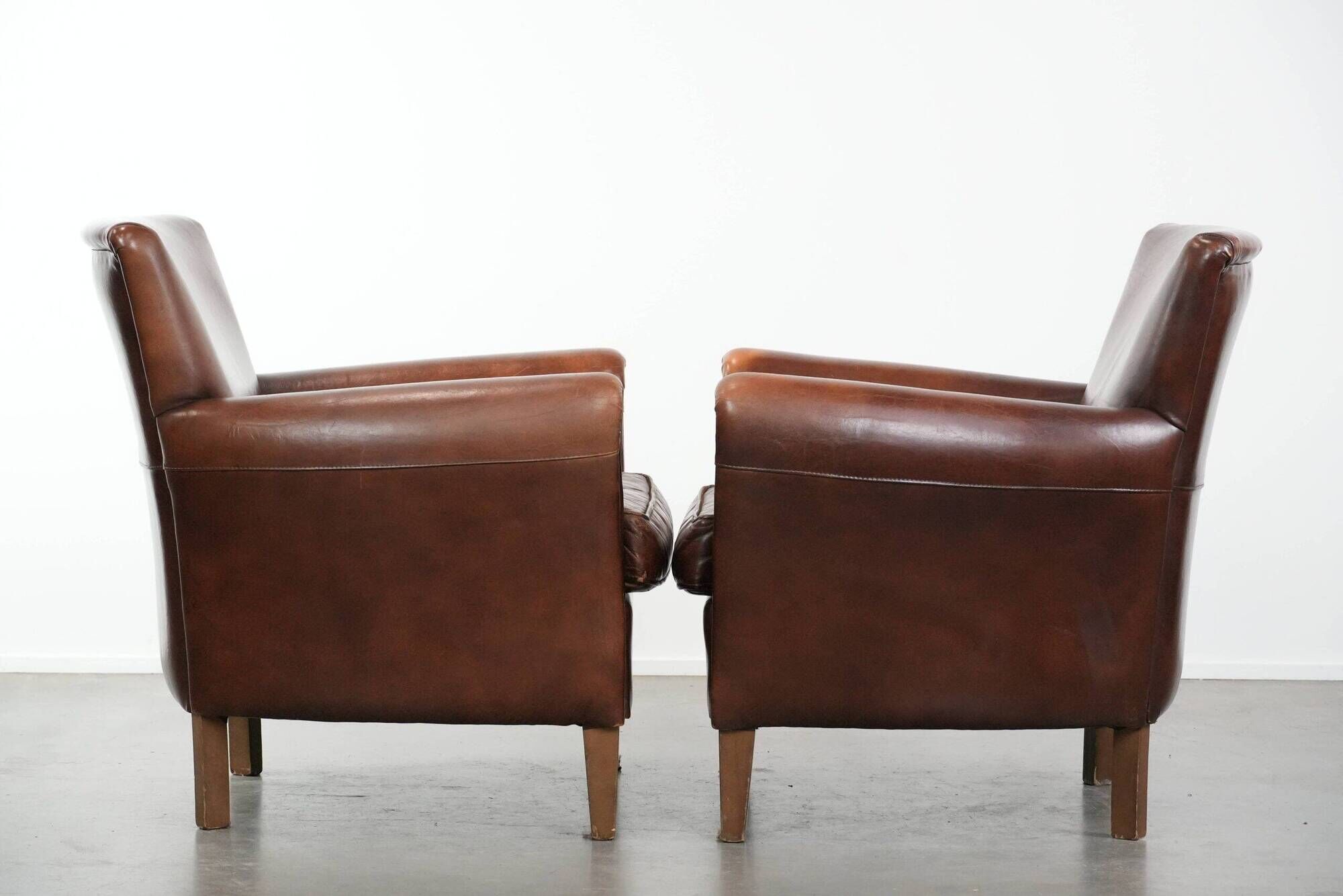 Ensemble de deux fauteuils en cuir de mouton vintage au caractère marqué.