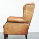 Large sheepskin wingback chair with black piping and decorative nails