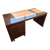Large wooden desk with a glass top and a wheeled drawer unit.