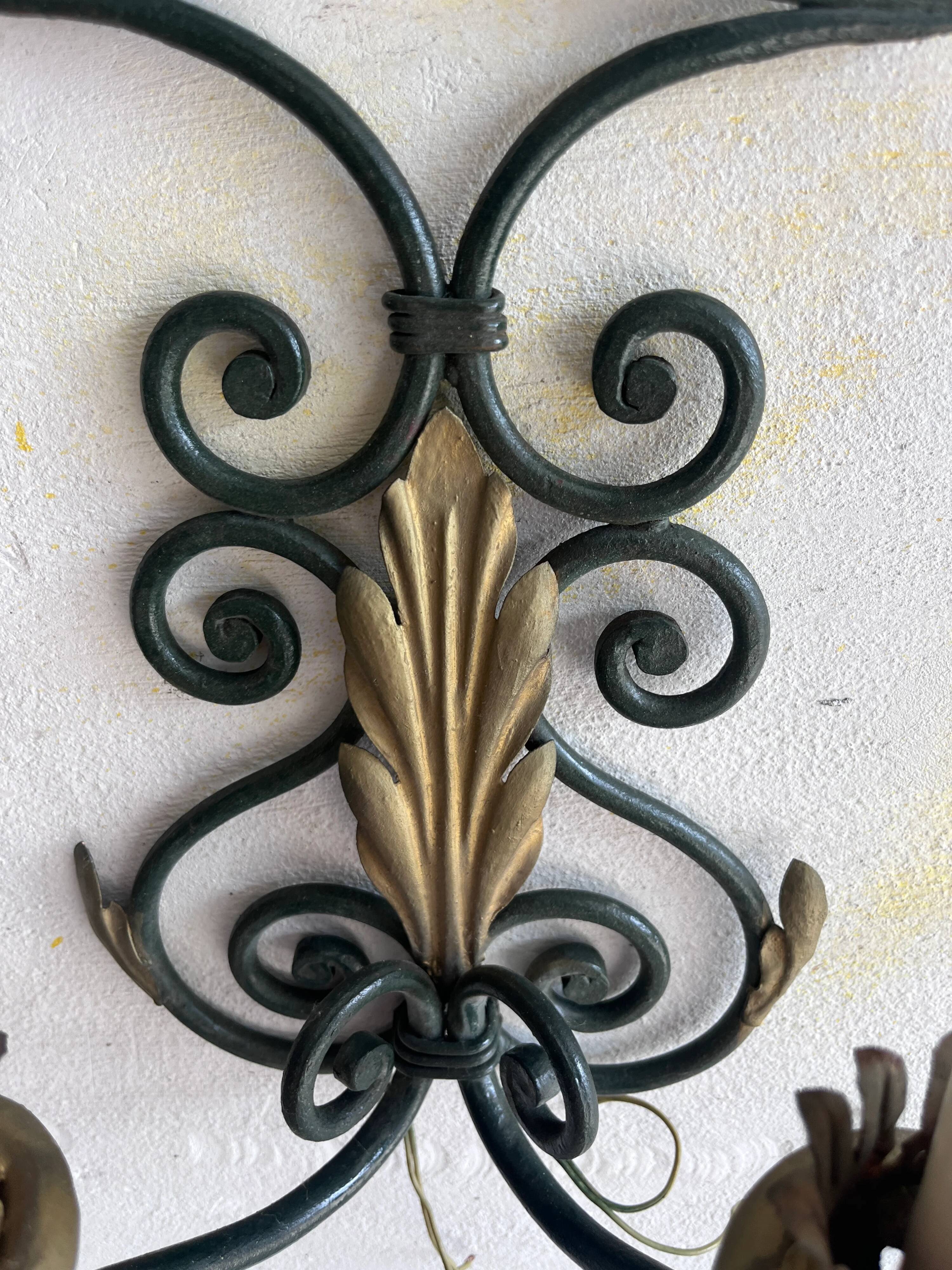 Pair of wall sconces in wrought iron with golden leaf patterns.