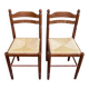 2 square wooden kitchen chairs with straw seats.
