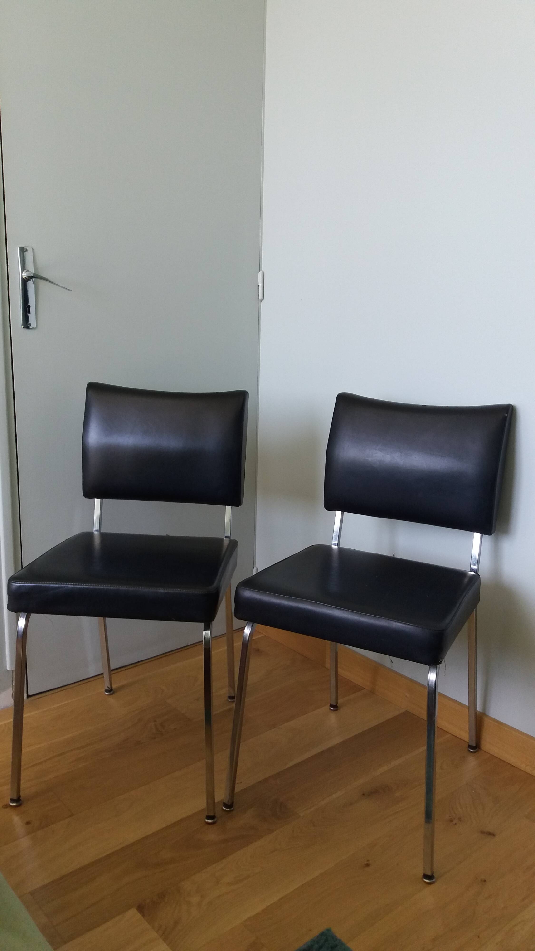 Chrome metal chairs and black faux leather upholstery in retro modernist style.