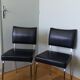 Chrome metal chairs and black faux leather upholstery in retro modernist style.