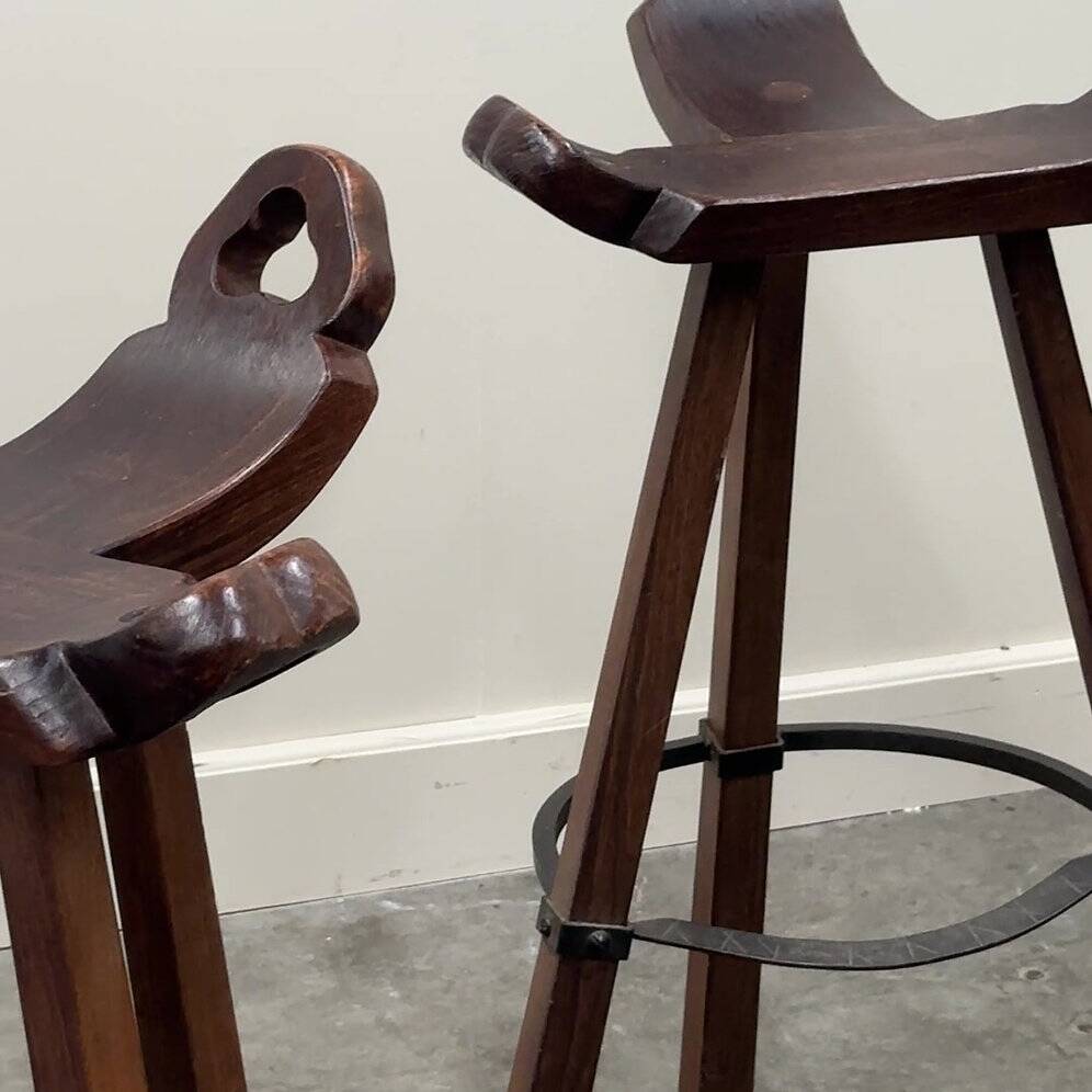 Set of 3 rustic carved oak bar stools with iron footrests, 1970s