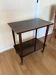 Vintage varnished wooden side table, on wheels with golden trim.