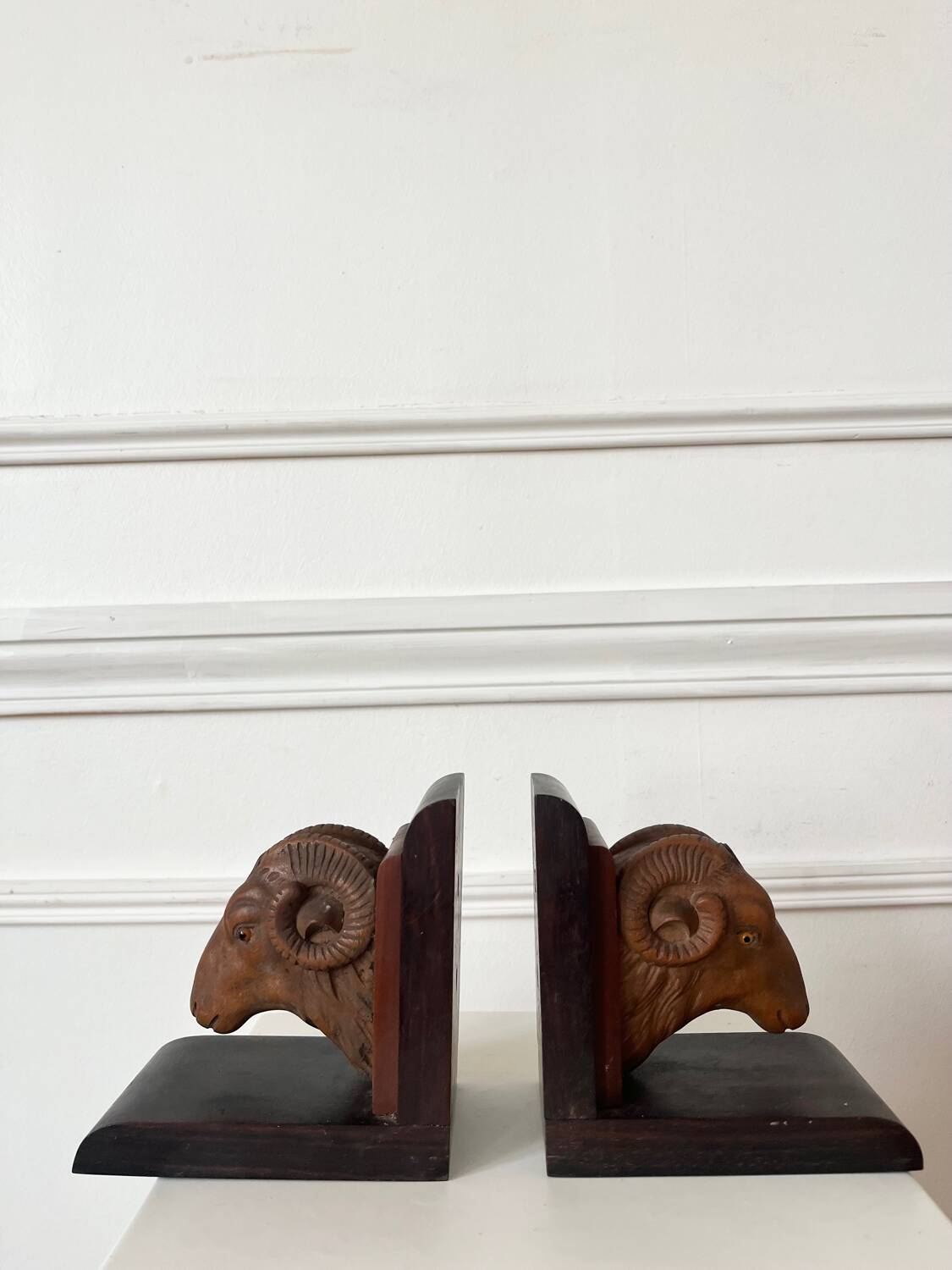 Pair of carved wooden bookends in the shape of ram's heads.
