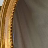 Oval-shaped wooden mirror in gold color
