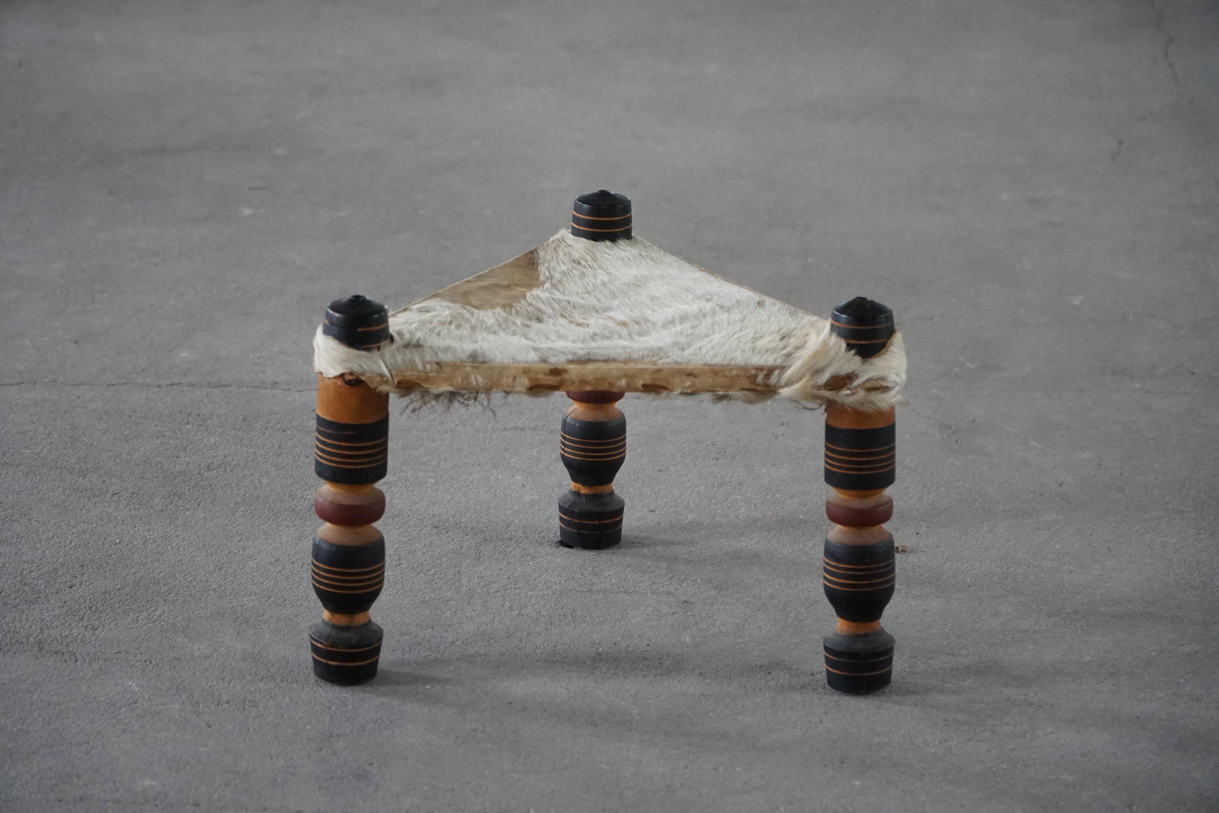 Vintage African artisanal stool, triangular shape with 3 legs, cowhide, 20th century.