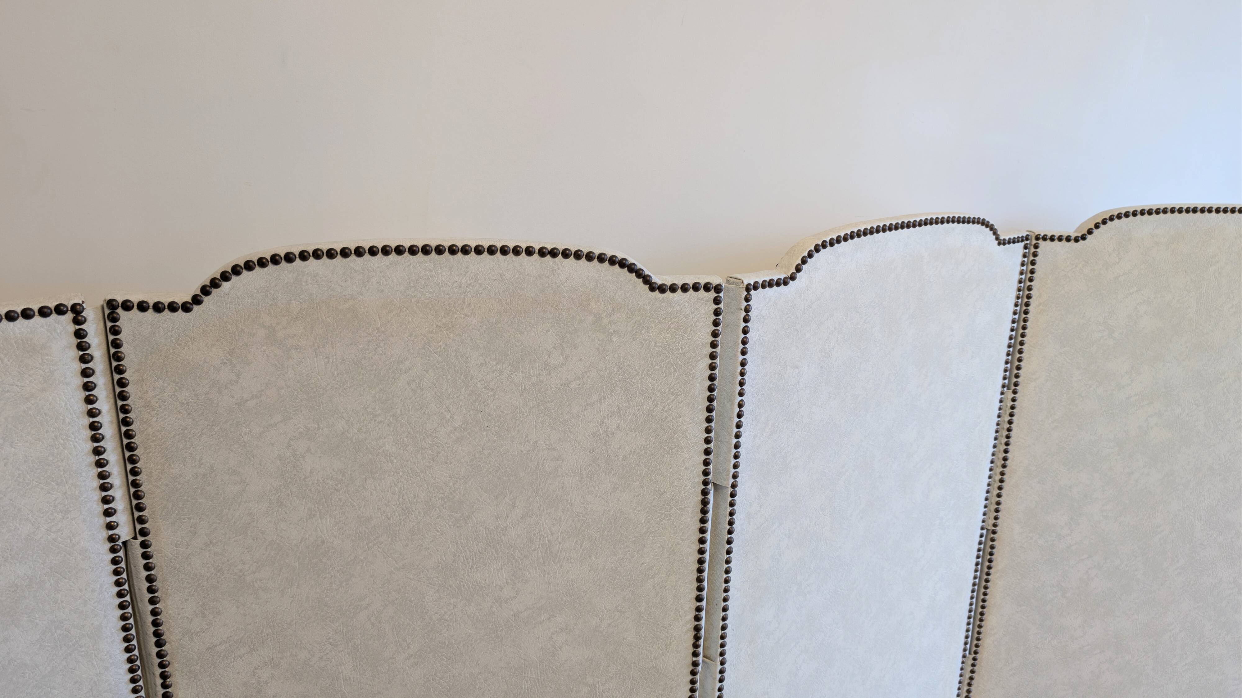 Vintage white faux leather screen with four studded panels, elegant decor.