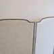 Vintage white faux leather screen with four studded panels, elegant decor.