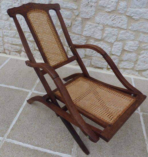 Antique folding chair with caned seat and backrest made of wood.