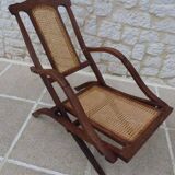 Antique folding chair with caned seat and backrest made of wood.