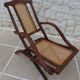 Antique folding chair with caned seat and backrest made of wood.