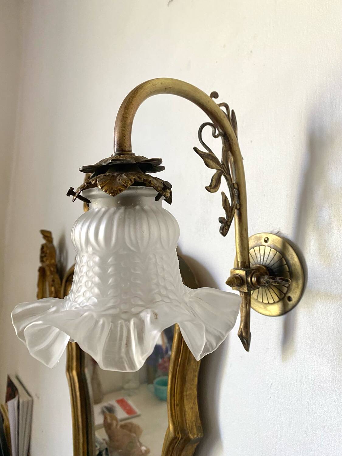 Antique brass wall light with glass shade.