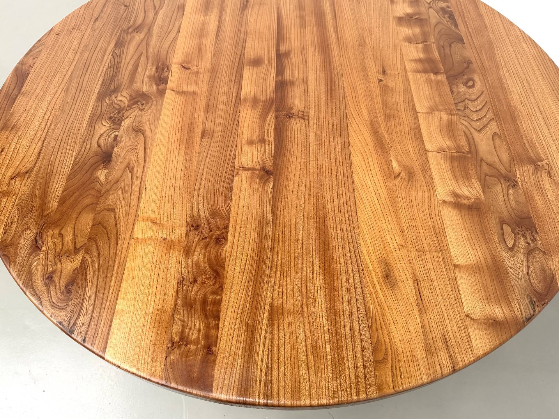 Modernist round table in solid elm, crossed legs.