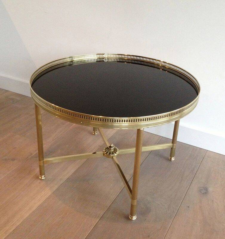 Round coffee table in brass with a black lacquered glass top by Maison Jansen.