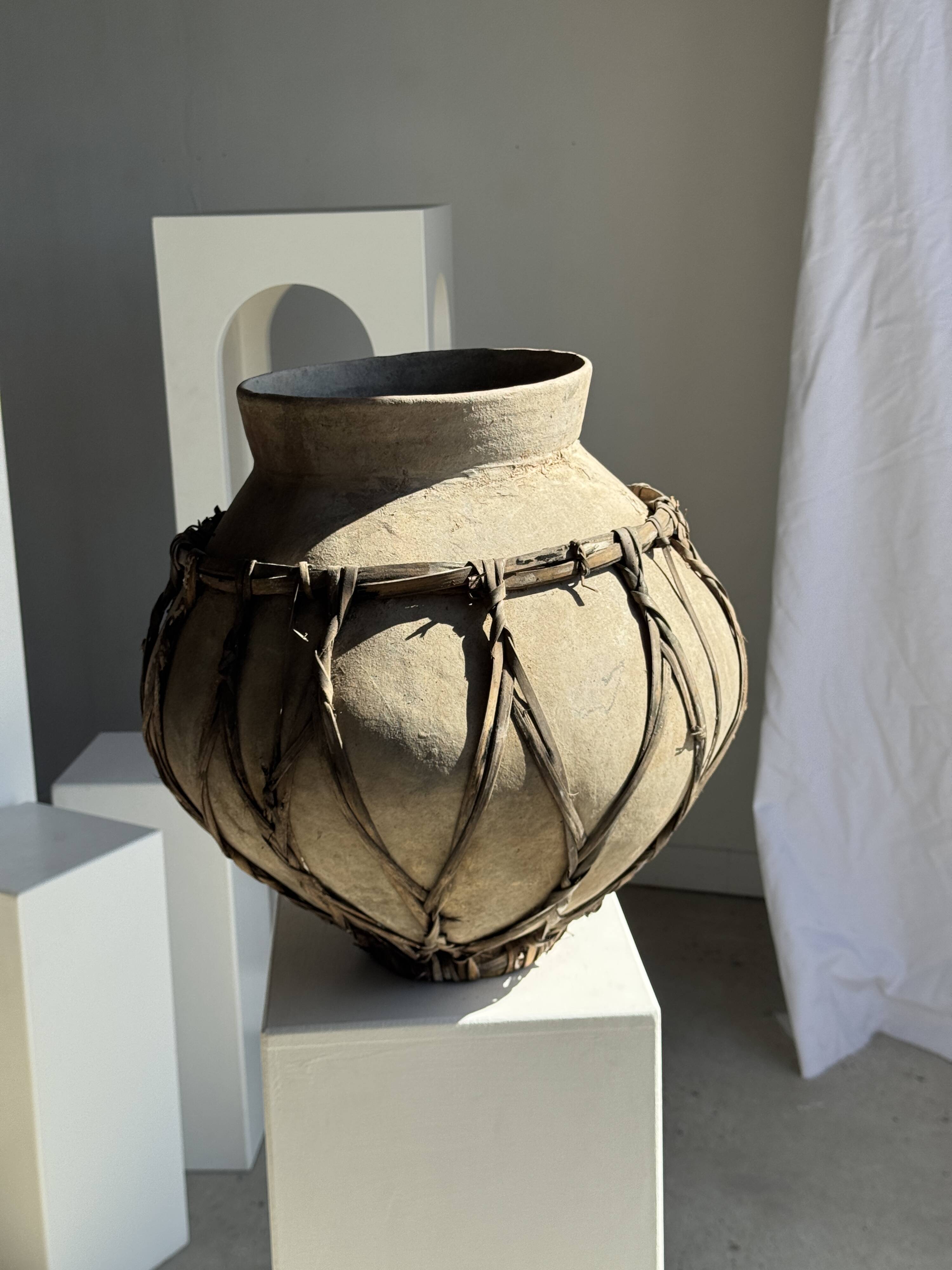 Very large light grey terracotta pot with handles and rattan crossbars.