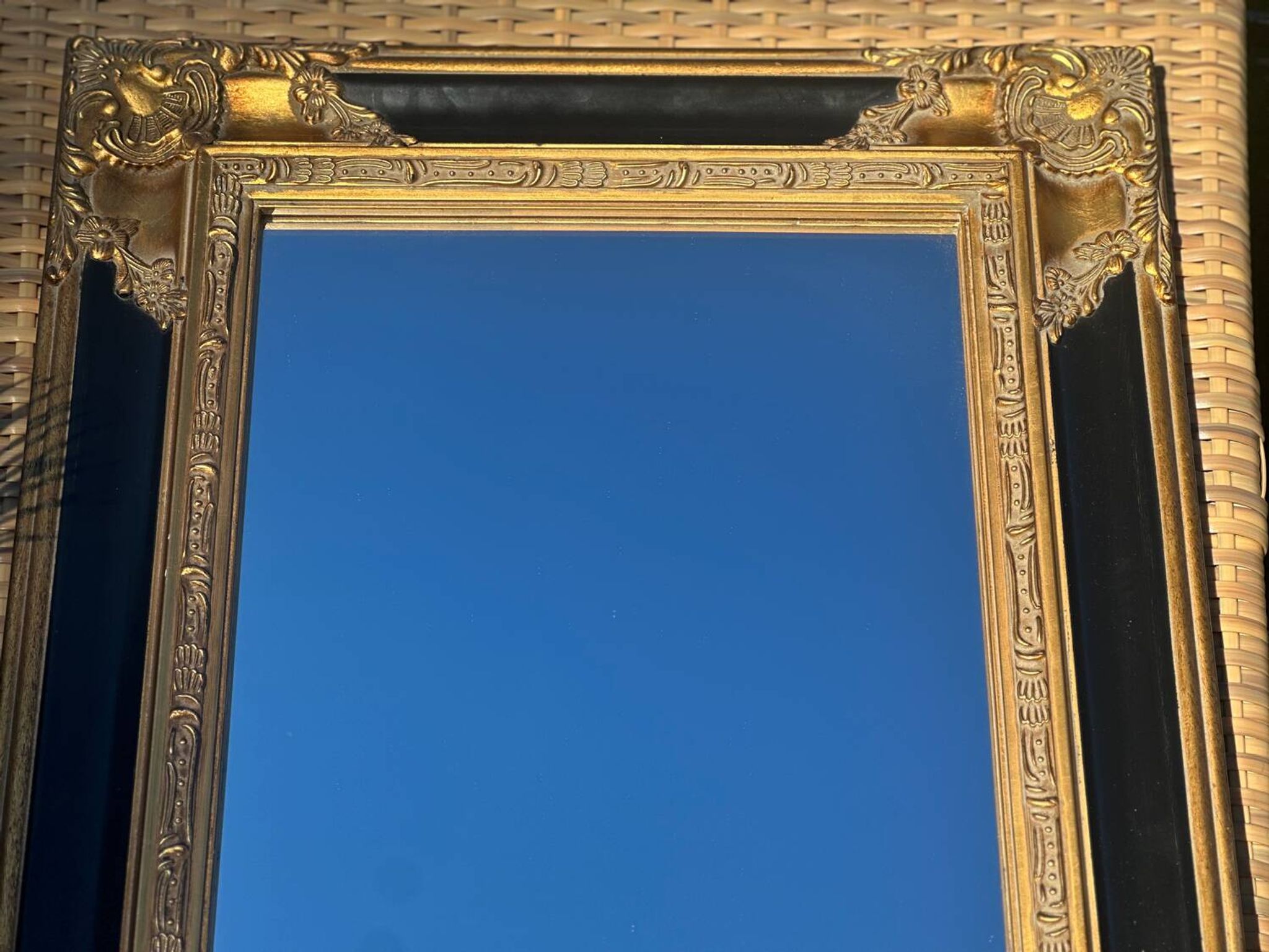 Miroir Baroque en bois doré sur fond noir.