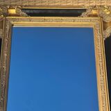 Baroque mirror in gilded wood on a black background.