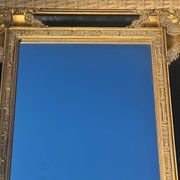 Miroir Baroque en bois doré sur fond noir.
