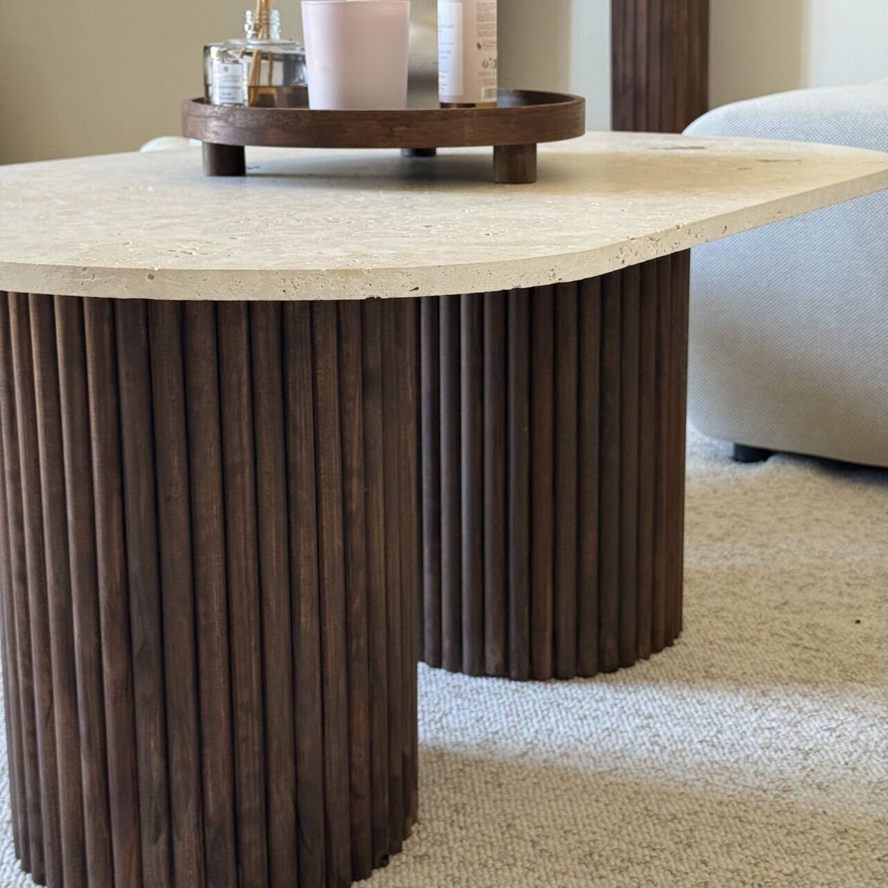 Oval coffee table in travertine and fluted wood.