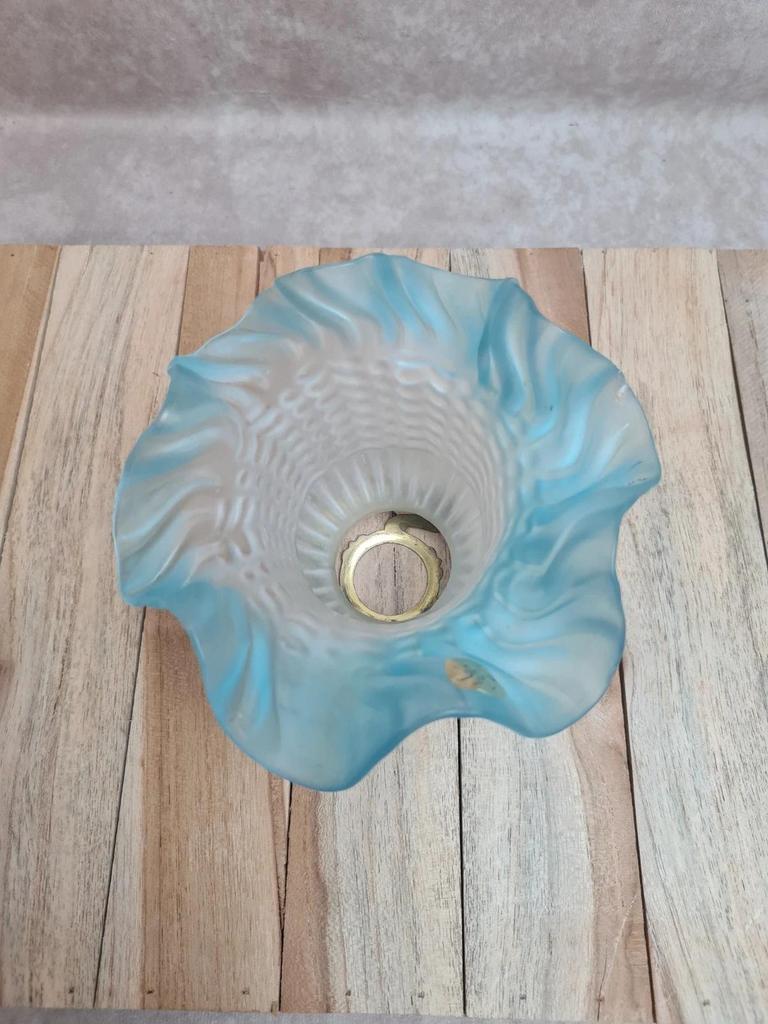 An antique lampshade in frosted glass with delicate blue edges.