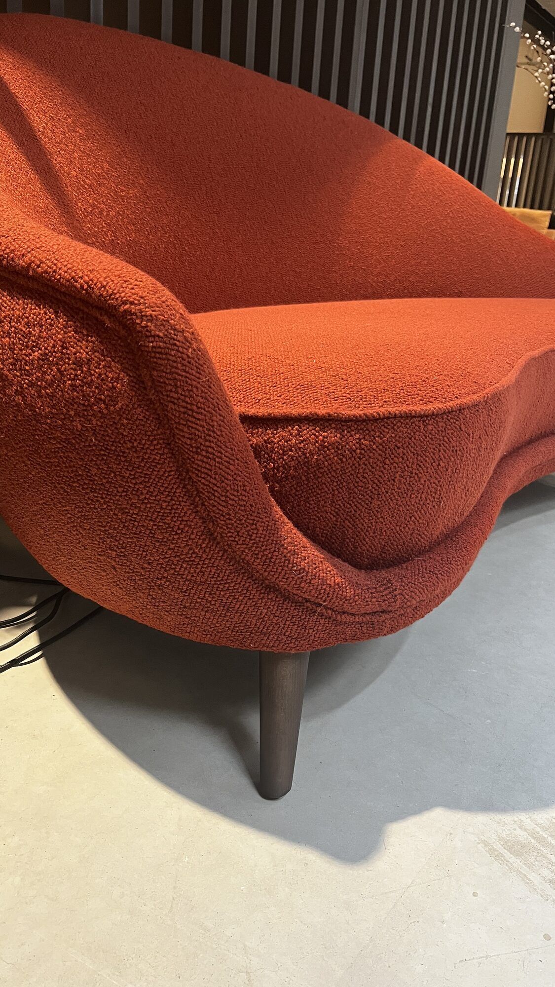 Two-seater sofa in red/orange boucle fabric.