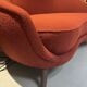 Two-seater sofa in red/orange boucle fabric.
