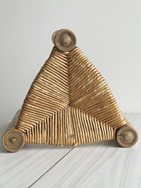 Antique tripod stool in light wood with a woven straw seat.