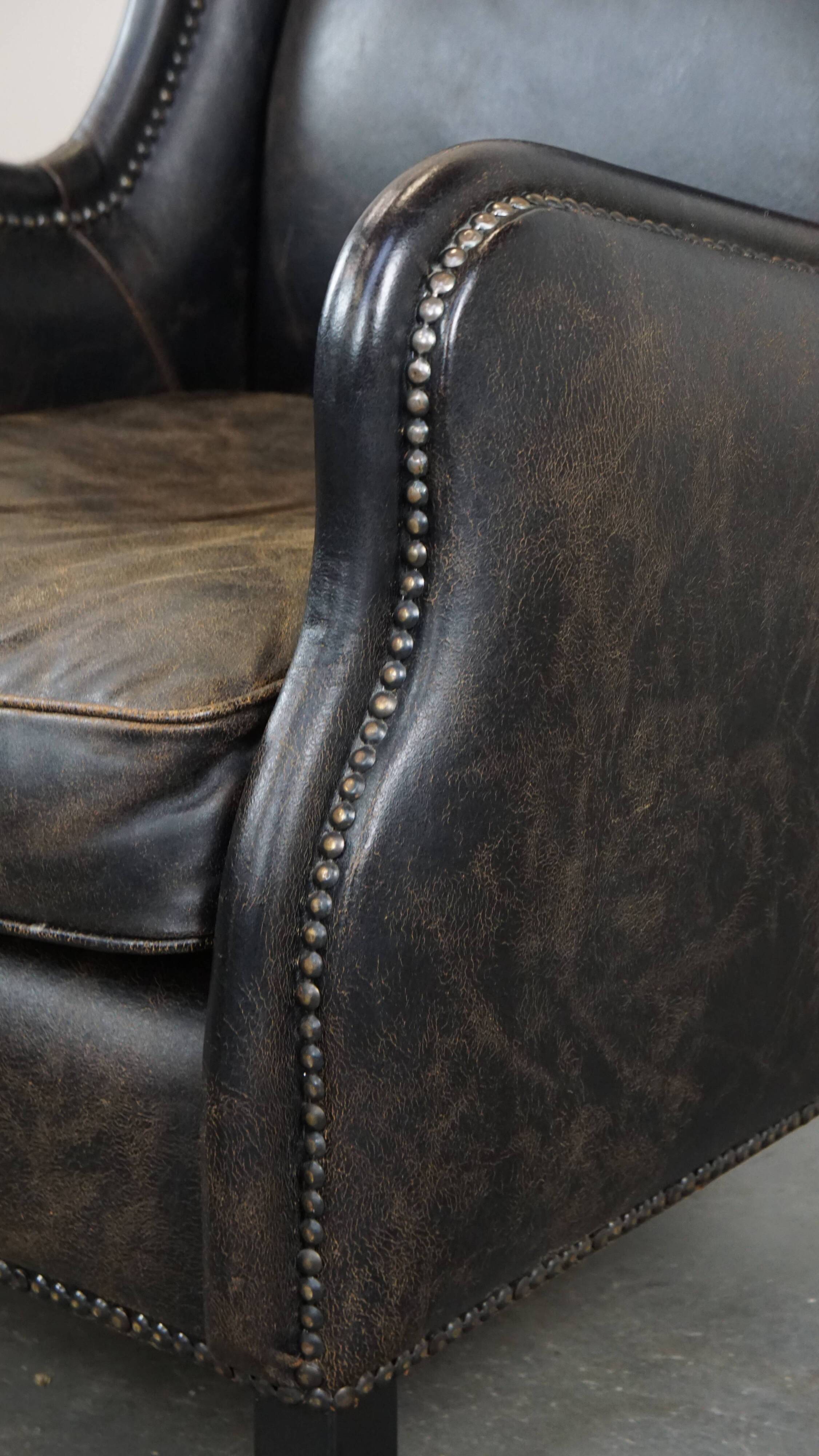 Black cow leather armchair in industrial style finished with decorative nails