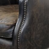 Black cow leather armchair in industrial style finished with decorative nails