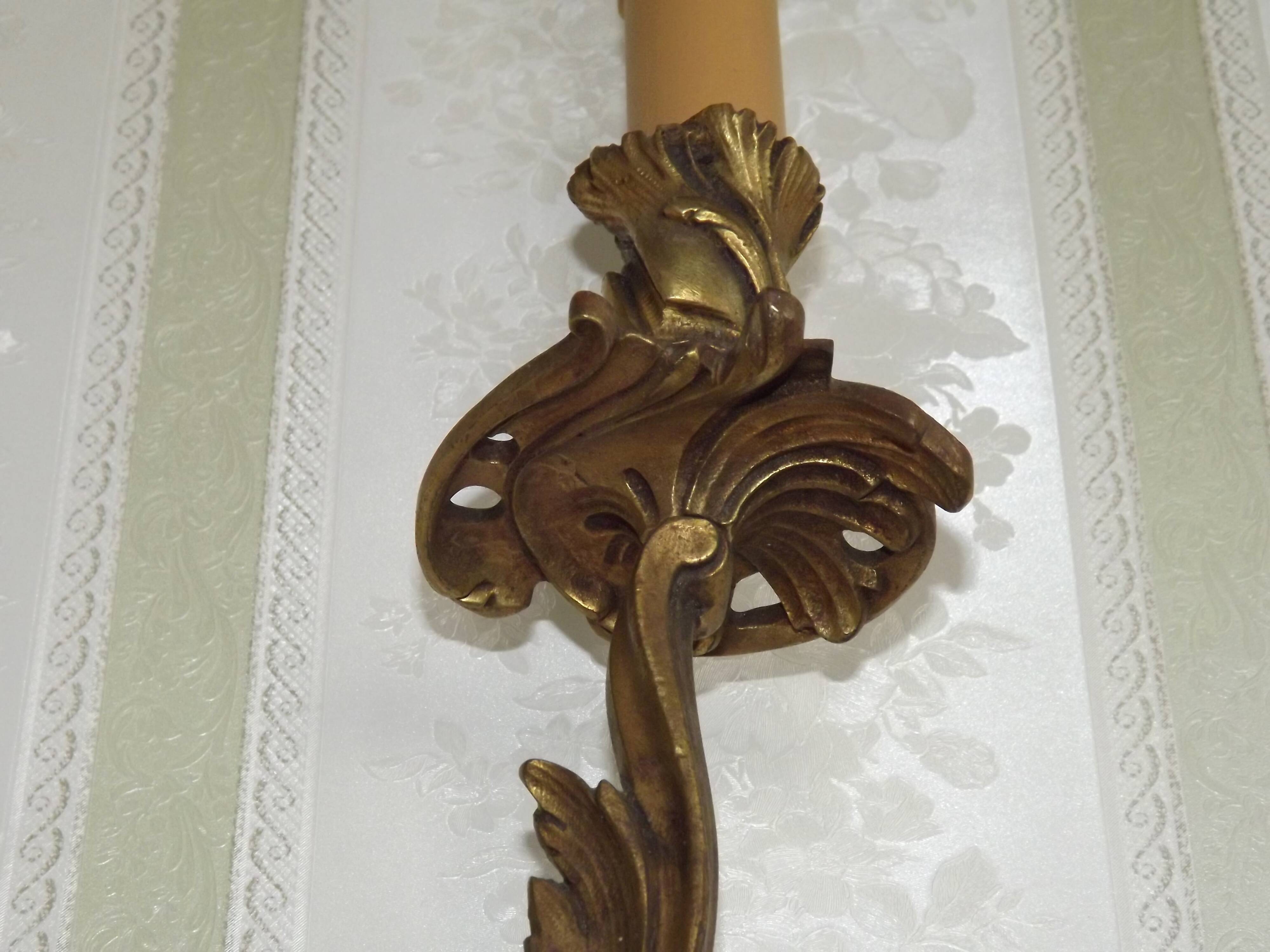 Apply two bronze wall lights decorated with acanthus leaves.